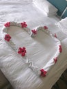 Heart with flowers decor on a bed in hotel room Royalty Free Stock Photo