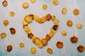 Heart of fruit chips framed with pieces of dried fruit on a blue scratched background