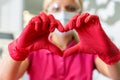 Heart gesture made by doctor`s hands wearing red rubber medical gloves