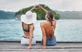 Heart hands, back and girl friends by a lake while on a summer, paradise and tropical vacation. River, dock and women Royalty Free Stock Photo