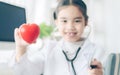 Heart in the hands of the Cute child in doctor coat with stethoscope . Love concept. Health concept