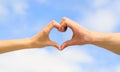 Heart from hands on a sky background. Love, friendship concept. Girl and male hand in heart form love blue sky. Female Royalty Free Stock Photo