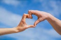 Heart from hands on a sky background. Love, friendship concept. Girl and male hand in heart form love blue sky. Female Royalty Free Stock Photo