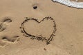 Heart handwritten on the sand on the beach and foam from the waves. Valentines day concept