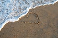 Heart handwritten on a sand of beach with wave