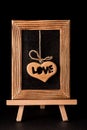 Heart hanging in old picture frame on black background. Royalty Free Stock Photo