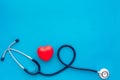 Heart health, health care concept. Stethoscope near rubber heart on blue background top view space for text