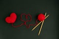 The heart is knitted of red threads on a dark background with a ball and wooden knitting needles. Royalty Free Stock Photo