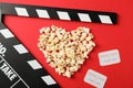 Heart laid out from popcorn, clapperboard and tickets on red background Royalty Free Stock Photo