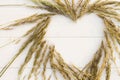 Heart laid out of spikelets on white wooden background. Flat lay. Copy space Royalty Free Stock Photo