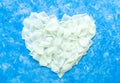 The heart is lined with white rose petals on a sky blue background. Valentine`s Day decoration and love concept. A wedding postca Royalty Free Stock Photo