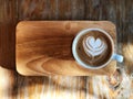 Heart love Latte art coffee in white cup the wooden tray and vintage wooden table.