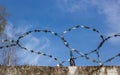 A heart made of barbed wire against a blue sky on a concrete fence.The object is protected Royalty Free Stock Photo