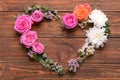 Heart made of beautiful flowers and leaves on wooden background Royalty Free Stock Photo