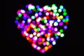 Heart made of blurred rainbow circles of light on a black background