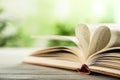 Heart made of book pages on wooden table against background, closeup. Space for text Royalty Free Stock Photo