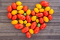 Heart made of bright ripe yellow and red cherry tomatoes with place for inscription on wooden table Royalty Free Stock Photo