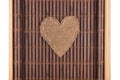 Heart made of burlap lies on a bamboo mat with curved edges. Royalty Free Stock Photo