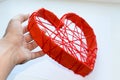 Heart made of cardboard and with red threads in a man& x27;s hand.