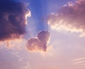 Heart of clouds with sun light rays on blue sky. Love symbol in sunrise or sunset colors Royalty Free Stock Photo