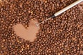 heart made of coffee beans and metal handheld milk steamer on brown background. Handheld frother or foam maker