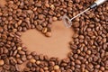 heart made of coffee beans and metal handheld milk steamer on brown background. Handheld frother or foam maker