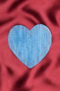 Heart made of denim fabric with yellow stitching on red silk