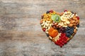 Heart made of different dried fruits and nuts on wooden background, top view. Royalty Free Stock Photo