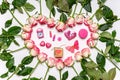 Heart made of fresh pink roses flowers and holiday decorations on white background. Greeting card, happy Valentine`s day concept. Royalty Free Stock Photo