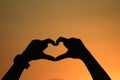 Heart made hands forming heart shape with gold sunset silhouette, Shadow of woman hand love signs in happy playing feel evening Royalty Free Stock Photo