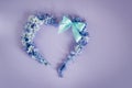 Heart made from hyacinths blossoms and mint bow on purple background. Royalty Free Stock Photo