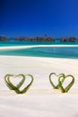 Heart made of palm tree leaves on tropical island with overwater bungalows in the background. Royalty Free Stock Photo