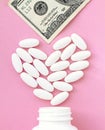 Heart made of pills and money over the neck of a bottle. Expensive medicine and venal love on pink background Royalty Free Stock Photo