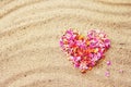 Heart made of pink petals of tropical flowers on the sand, close-up, top view. Royalty Free Stock Photo
