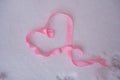 heart made of pink ribbon on clean snow