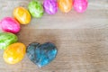 Heart made of precious stone on wood with colorful Easter eggs