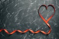 Heart made of red silk ribbon on a black stone background. Valentine`s Day. Top view, flat lay Royalty Free Stock Photo