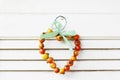 Heart made of rose hip fruits on wooden background