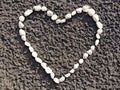 Heart made of small white pebbles on sand closeup Royalty Free Stock Photo