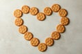 Heart made of tasty cracker biscuits on light background