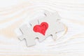 Heart made of two pieces of jigsaw puzzle on light wooden table, close-up Royalty Free Stock Photo