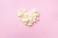 Heart made of white rose petals on pastel pink background. Top view, flat lay. Love and romantic concept. Copy space for your text Royalty Free Stock Photo