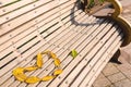 A heart made of yellow autumn leaves is laid out on a wooden white bench in the park. Royalty Free Stock Photo