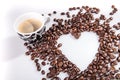 Heart make whit coffee beans and cup whit espresso and sweet heart cookie on white table background.