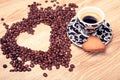 Heart make whit coffee beans and cup whit espresso and sweet heart cookie on wood table background. Royalty Free Stock Photo