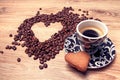 Heart make whit coffee beans and cup whit espresso and sweet heart cookie on wood table background. Royalty Free Stock Photo