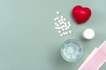 Heart, medical pills, cardiogram, glass of water, capsules on gray background. Royalty Free Stock Photo