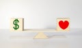 Heart and money on balance scale - Order of priority in life among love and money. Royalty Free Stock Photo
