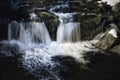 In the heart of the mountains in winter, at night, a river, the water falling on the foamy rocks and the snow on each side