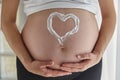 Heart painted with body cream on pregnant woman`s belly Royalty Free Stock Photo